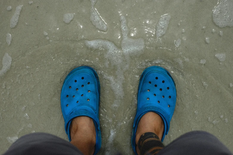 someone wearing blue slippers standing in water