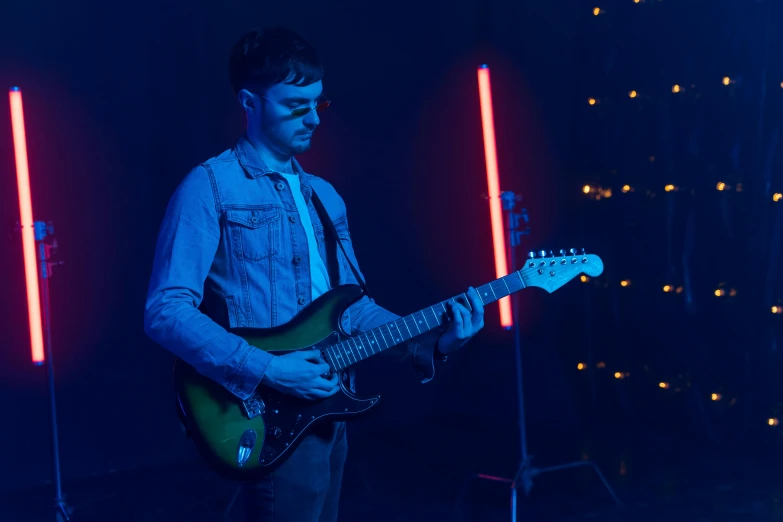 a man playing an electric guitar in a dark room with red lights