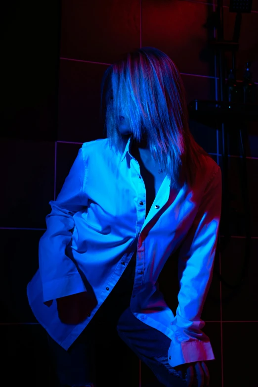 a woman sitting in the corner while wearing a blue jacket