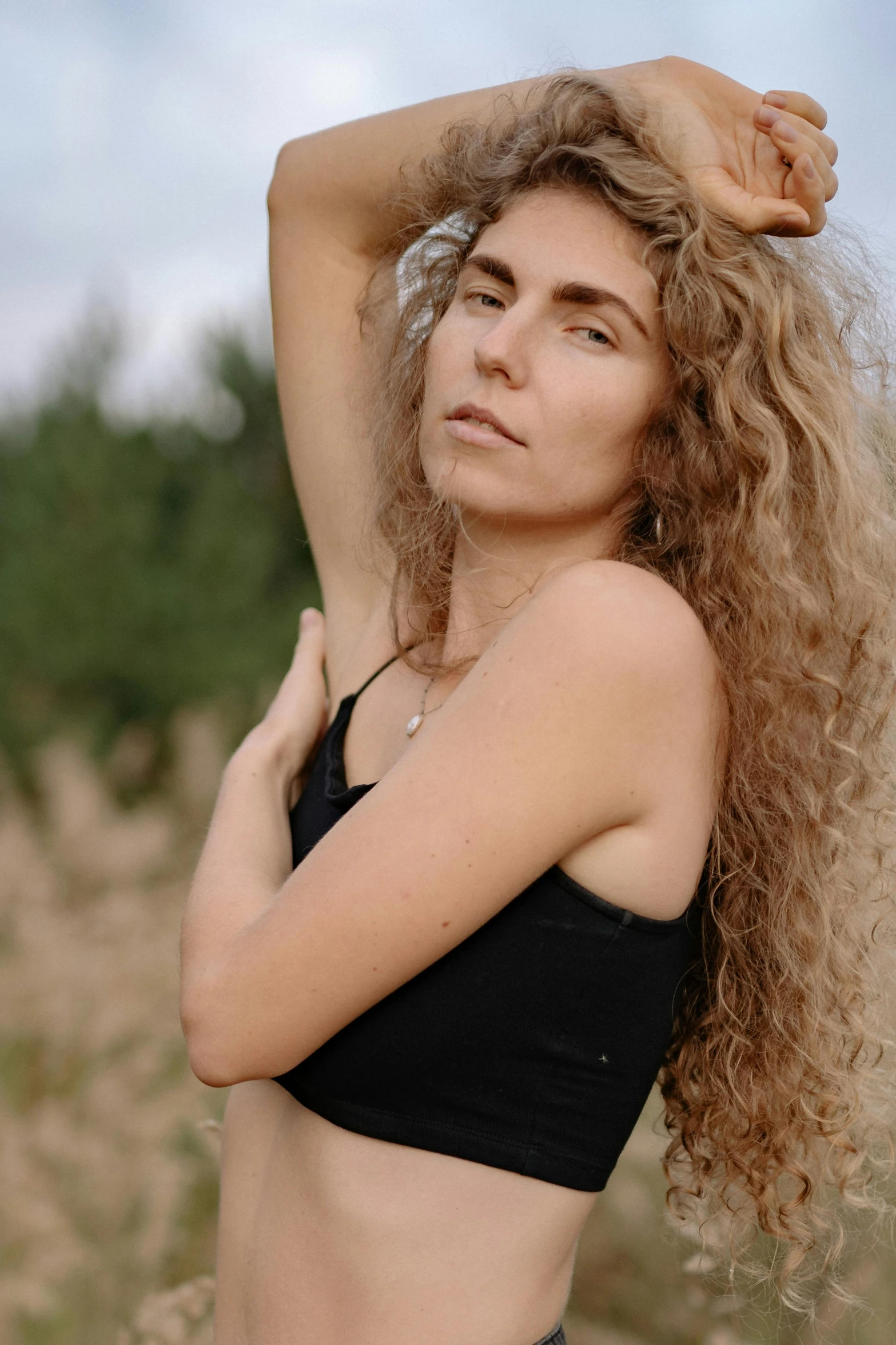 a woman with long hair and no  standing in grass