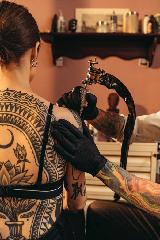 the tattoo artist holds a pipe with a man in the background