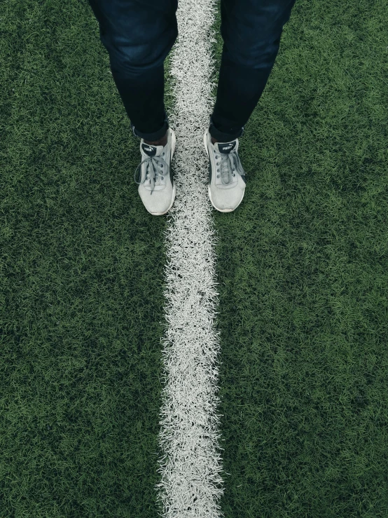 legs standing on grass with one foot up against the line