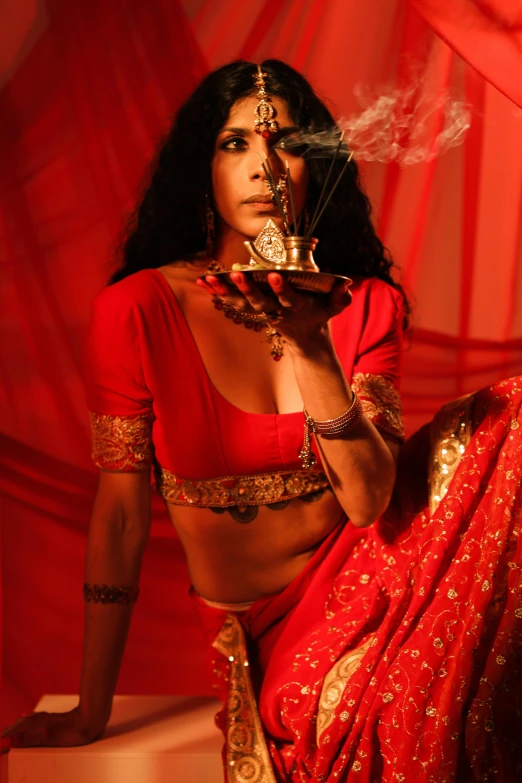 an indian woman wearing a red lehenga and smoking a pipe