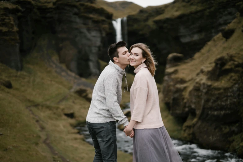a man and woman in grey clothes standing in front of a waterfall