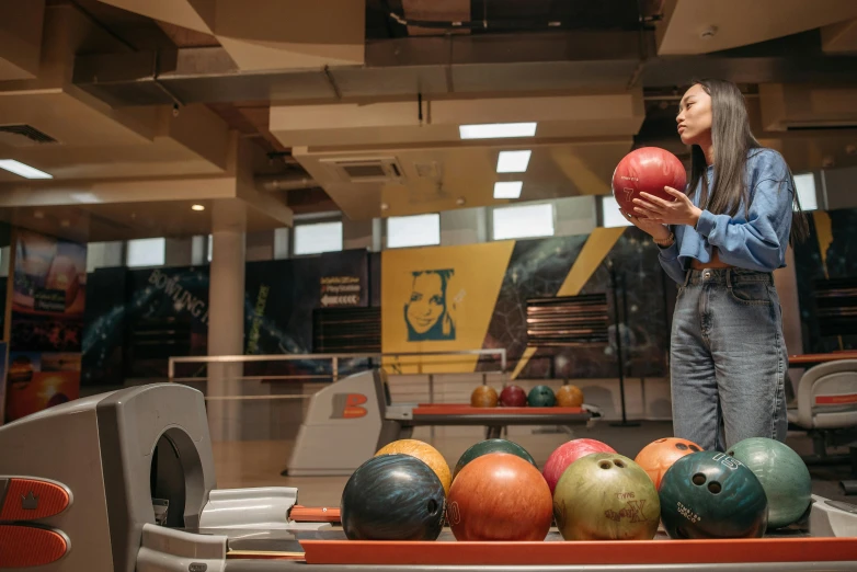 a young woman standing next to bowling balls in a room