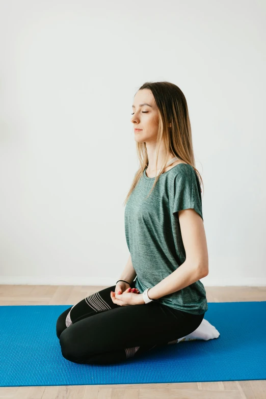 a girl is sitting on her yoga mat with her eyes closed