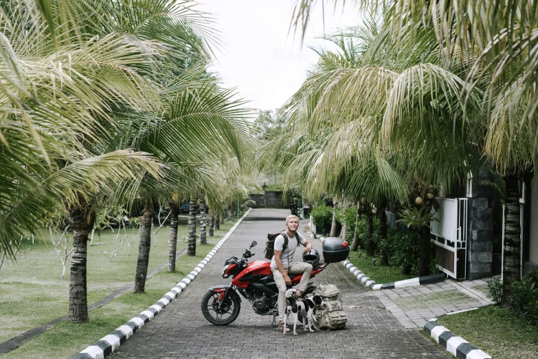 a man that is standing next to a red motorcycle