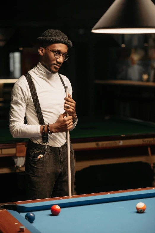 man standing in front of pool table wearing suspenders