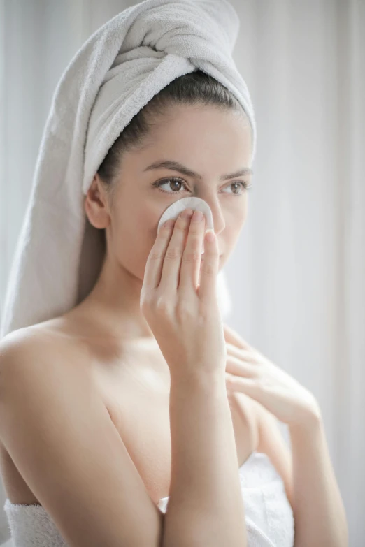 a woman with towel around her head wipes her nose