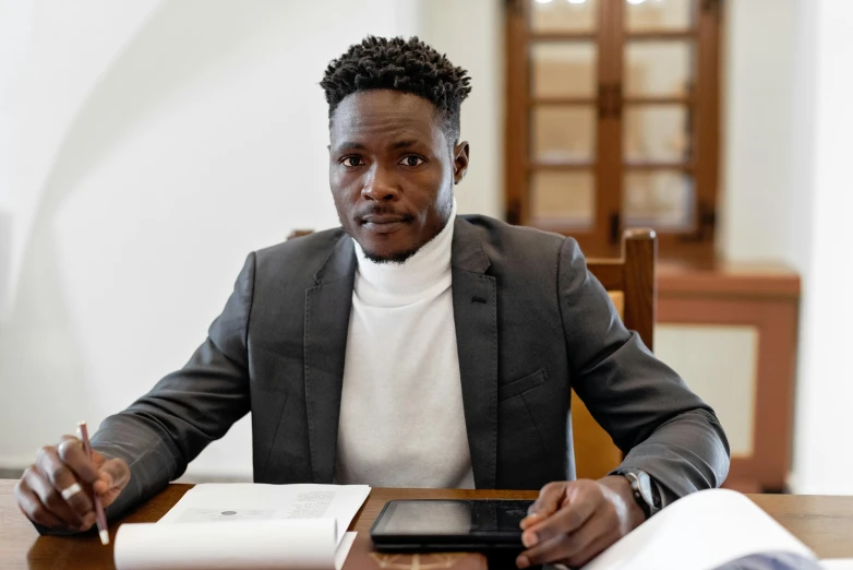 an african american man in business clothes is using a laptop computer at his desk