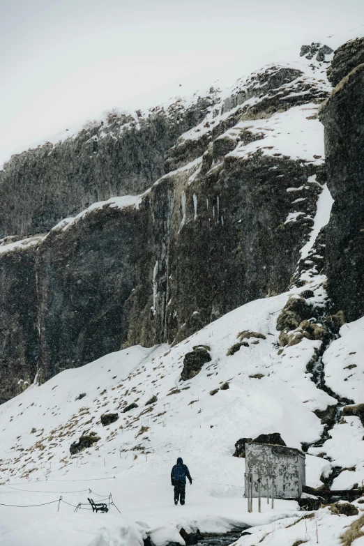 a man is walking in the snow uphill