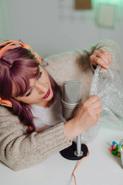 a young woman in head wraps, holding a microphone, and a microphone mic