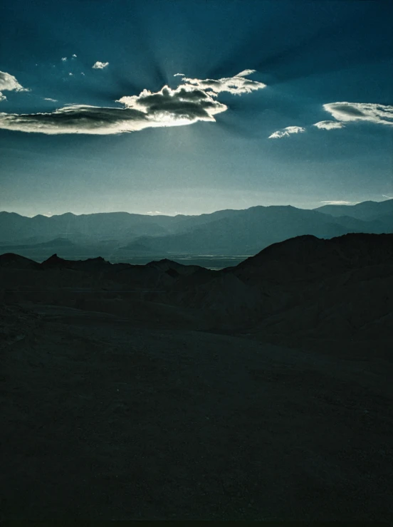 the sun shines in the distance as dark clouds hover over mountains