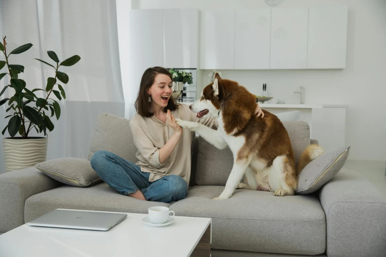 a woman is sitting on a couch with her dog