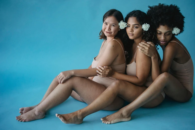 three beautiful women are sitting in front of a blue background