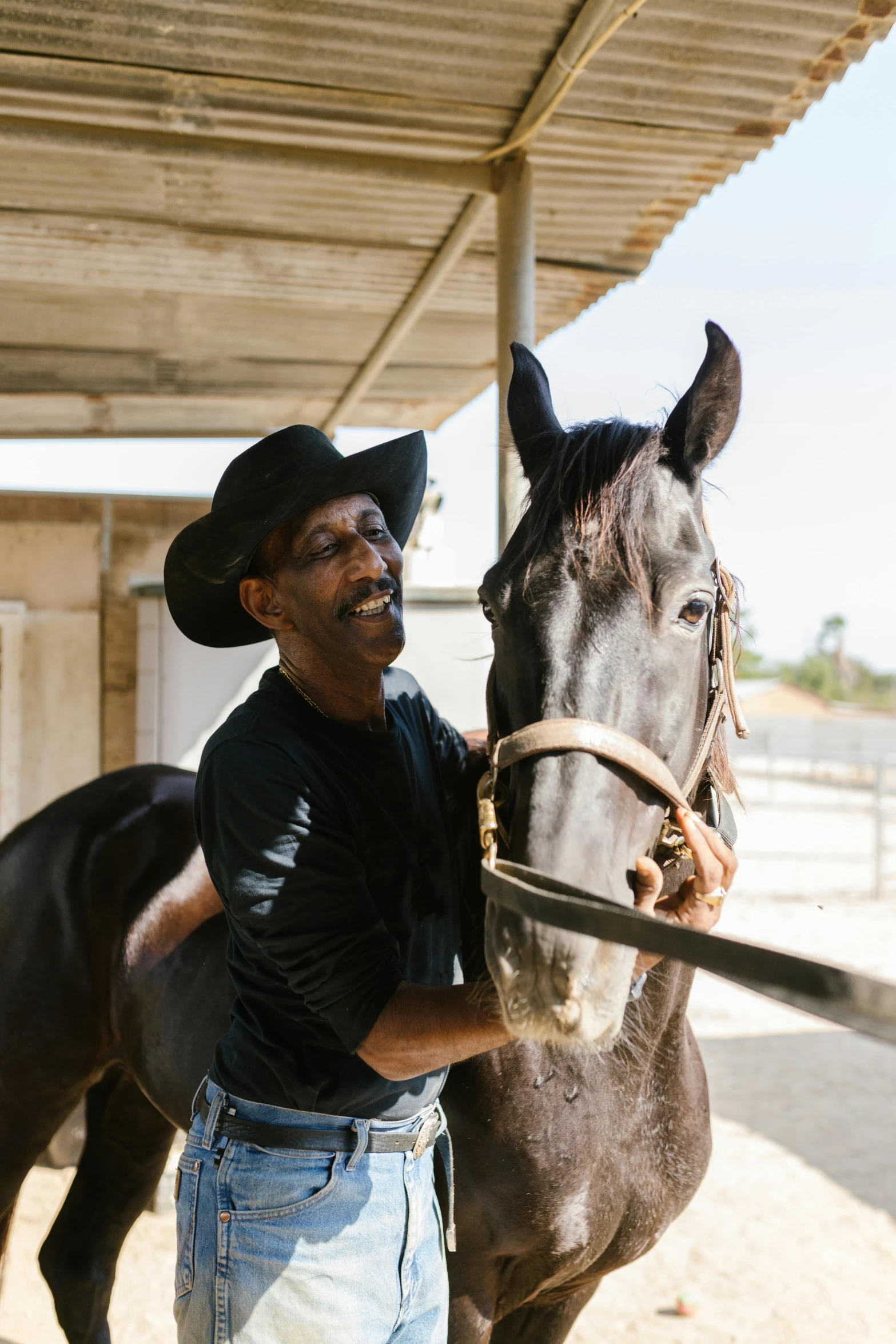 a man in a black shirt standing next to a brown horse