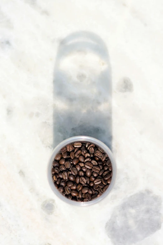 a round white container filled with coffee beans on a marble counter top