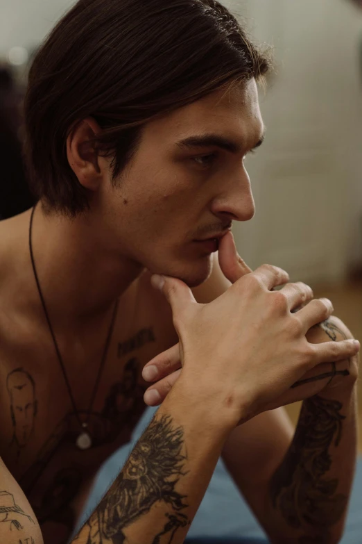 a young man with tattoos looking at soing