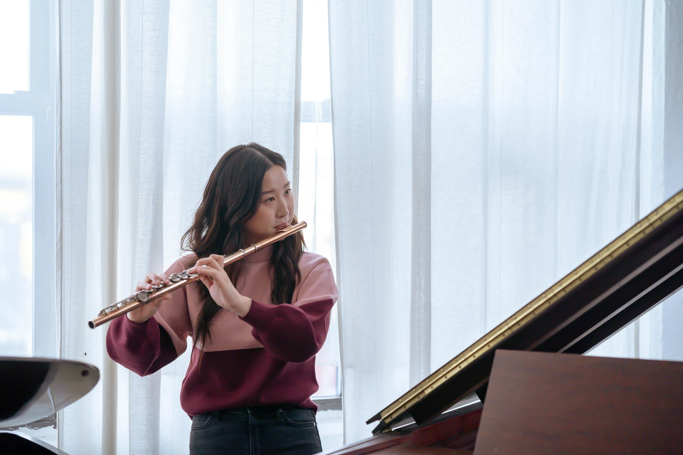 a woman playing a flute near a piano