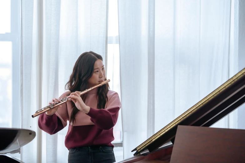 a woman playing a flute near a piano