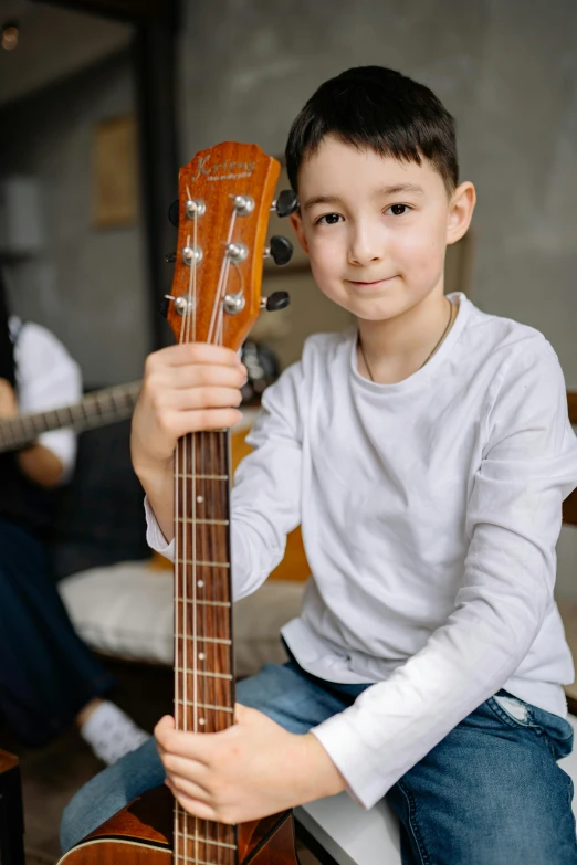 a boy is holding an old guitar in his hands