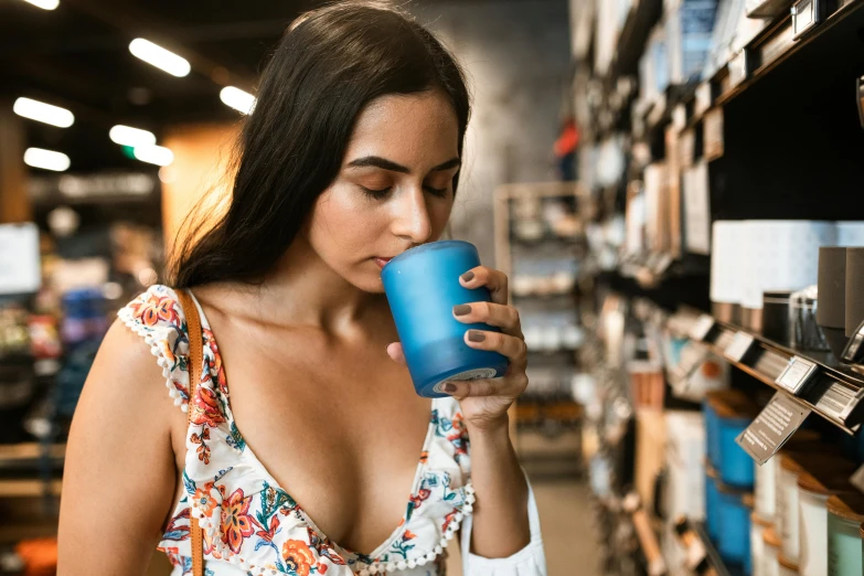 woman drinking cup of water in market shelf