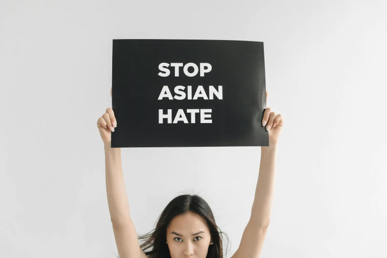 a person holds up a sign that says stop asian hate