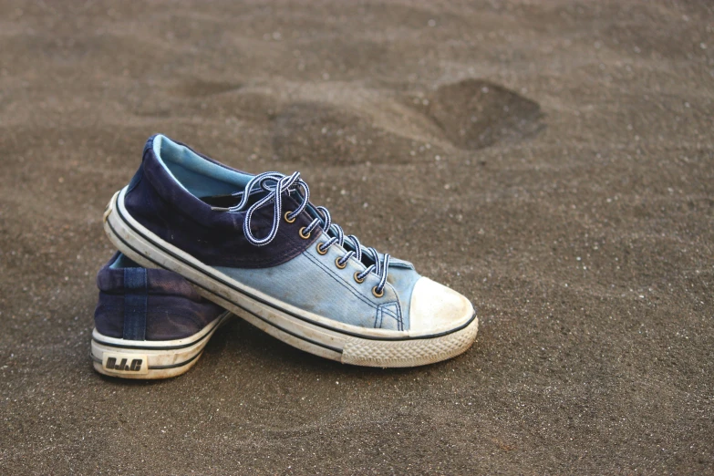 a pair of sneakers are on the ground near the sand