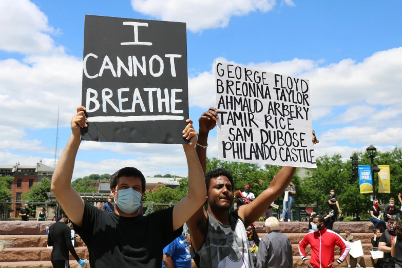 two people wearing masks holding up signs