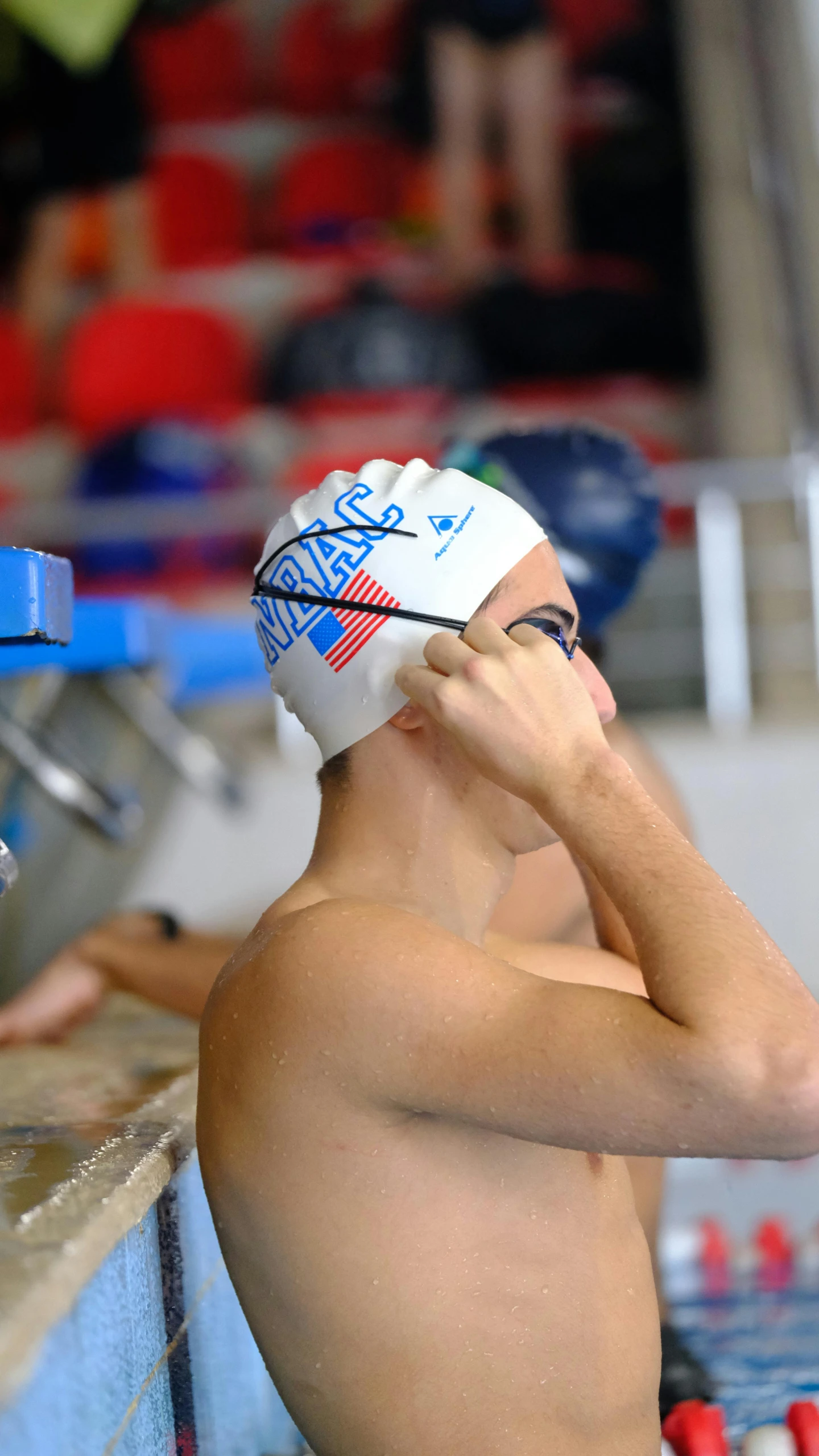 a boy with his hand over his face sitting next to the edge of a pool