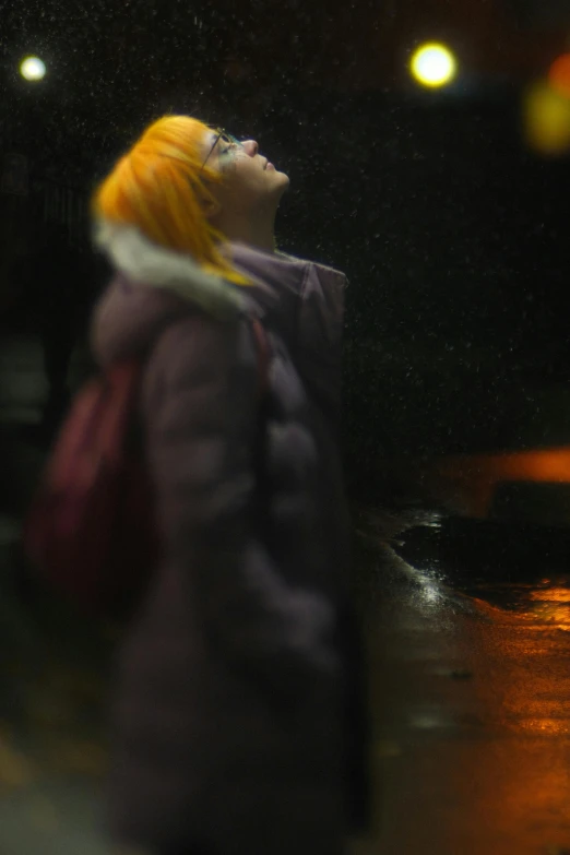 a woman in a purple coat with yellow hair stands near a sidewalk