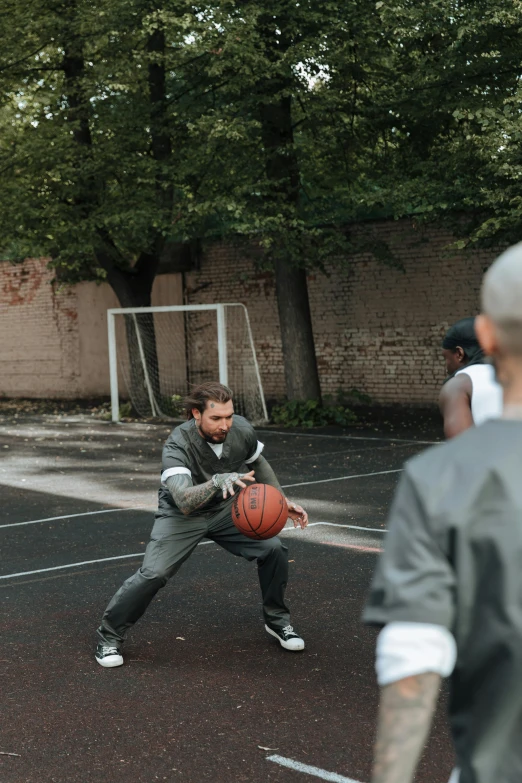 a young man is playing with a basketball while other players look on