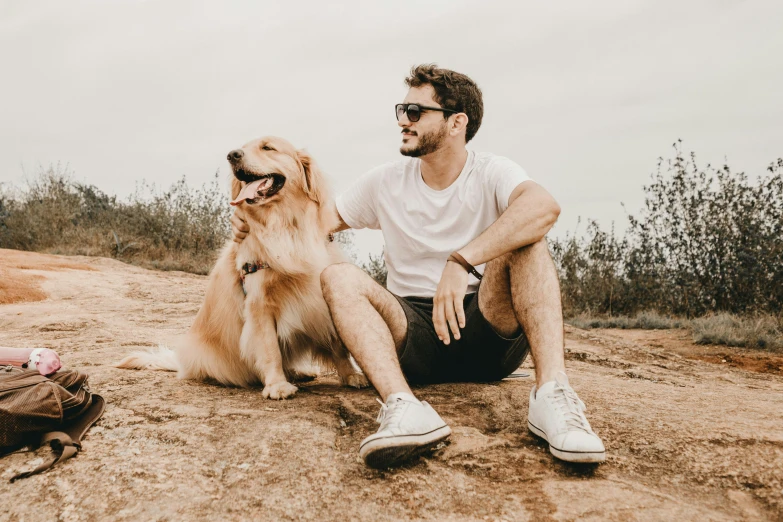 a man is sitting next to his dog and has its paws on the ground