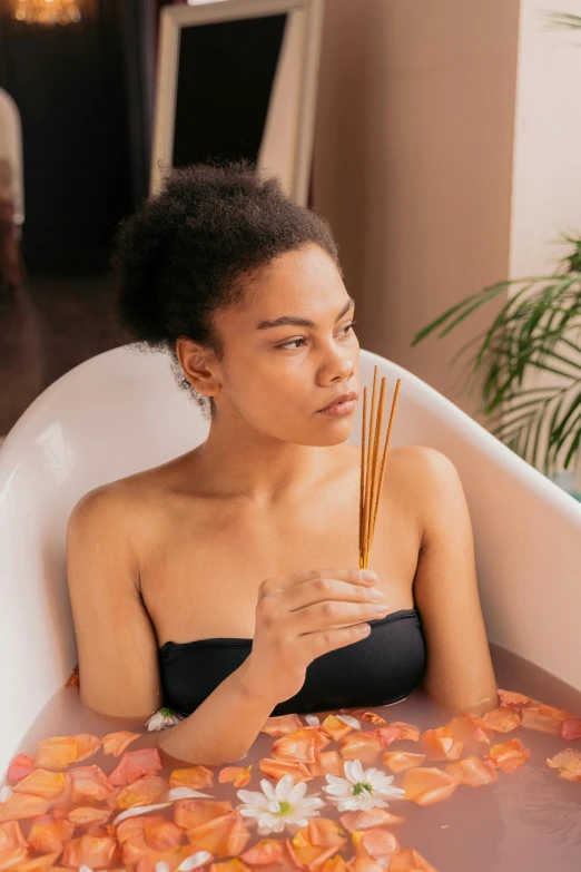 a woman in black  sitting in the  tub holding incense sticks