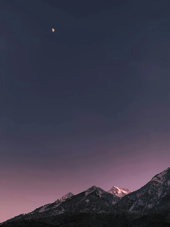 the moon and the two planets are in the sky above some mountain tops