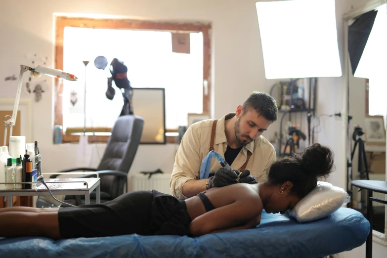 a man sitting next to a woman laying on top of a blue bed