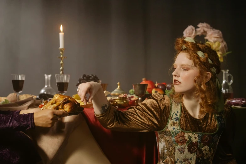 woman in renaissance clothing with glasses of wine seated at a table eating