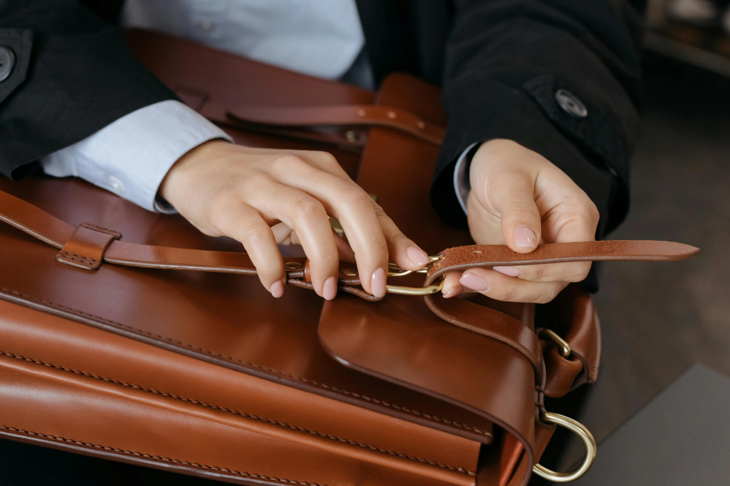 a person holding a leather briefcase while one man is wearing a tie