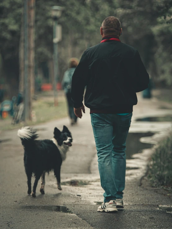 a person walking down the road while a dog walks beside him