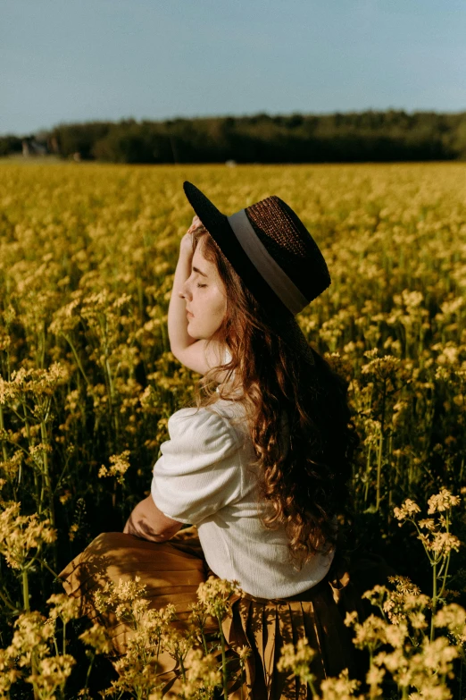 a woman standing in a field with a hat