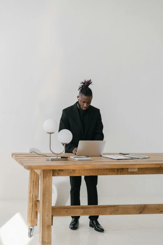 a woman wearing a black suit working on a white laptop