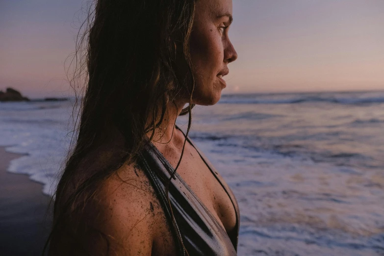 the back side of a woman in black top standing next to the ocean