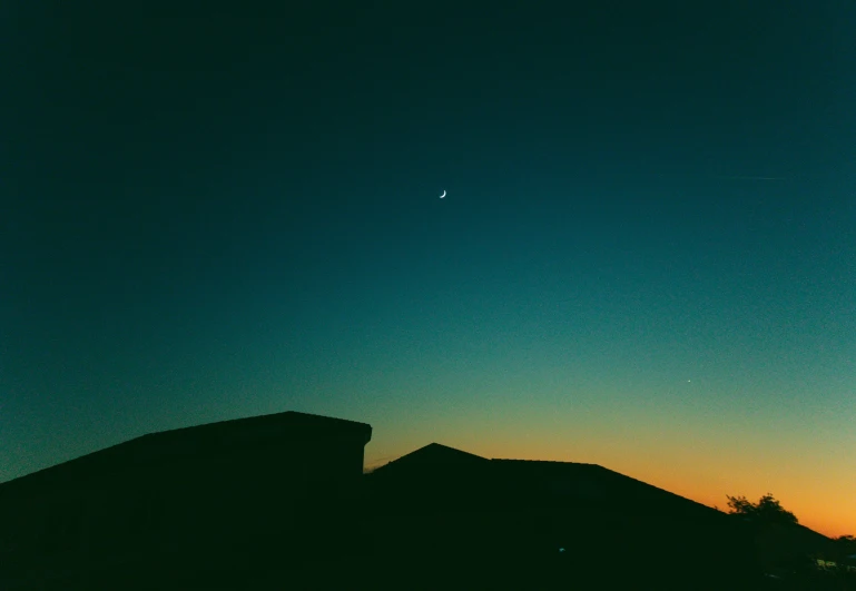 silhouettes of mountains at dusk and a distant bird in the sky