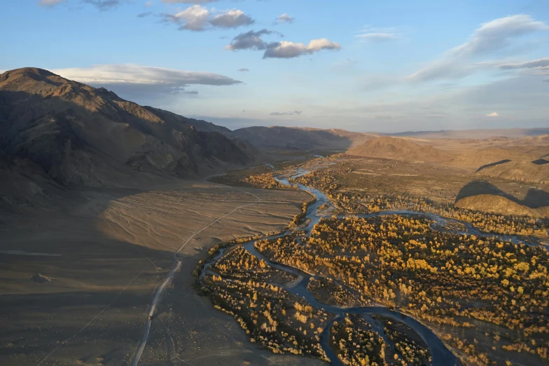 a river flowing through a desert plain under a cloudy blue sky