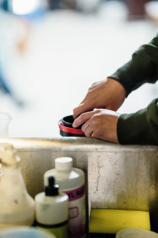 a persons hand with a soap and toothpaste on a counter