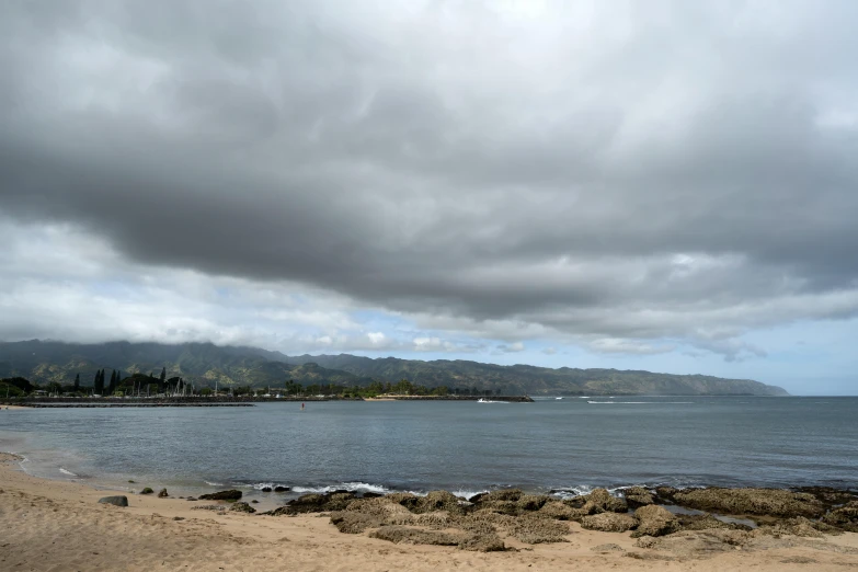 a cloudy view from the shore with boats on the ocean