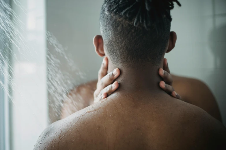 a woman holding her chest in pain from using a showerhead