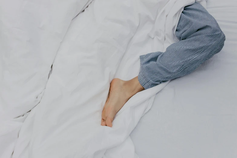 a woman is sleeping in a bed with her right foot on the pillow