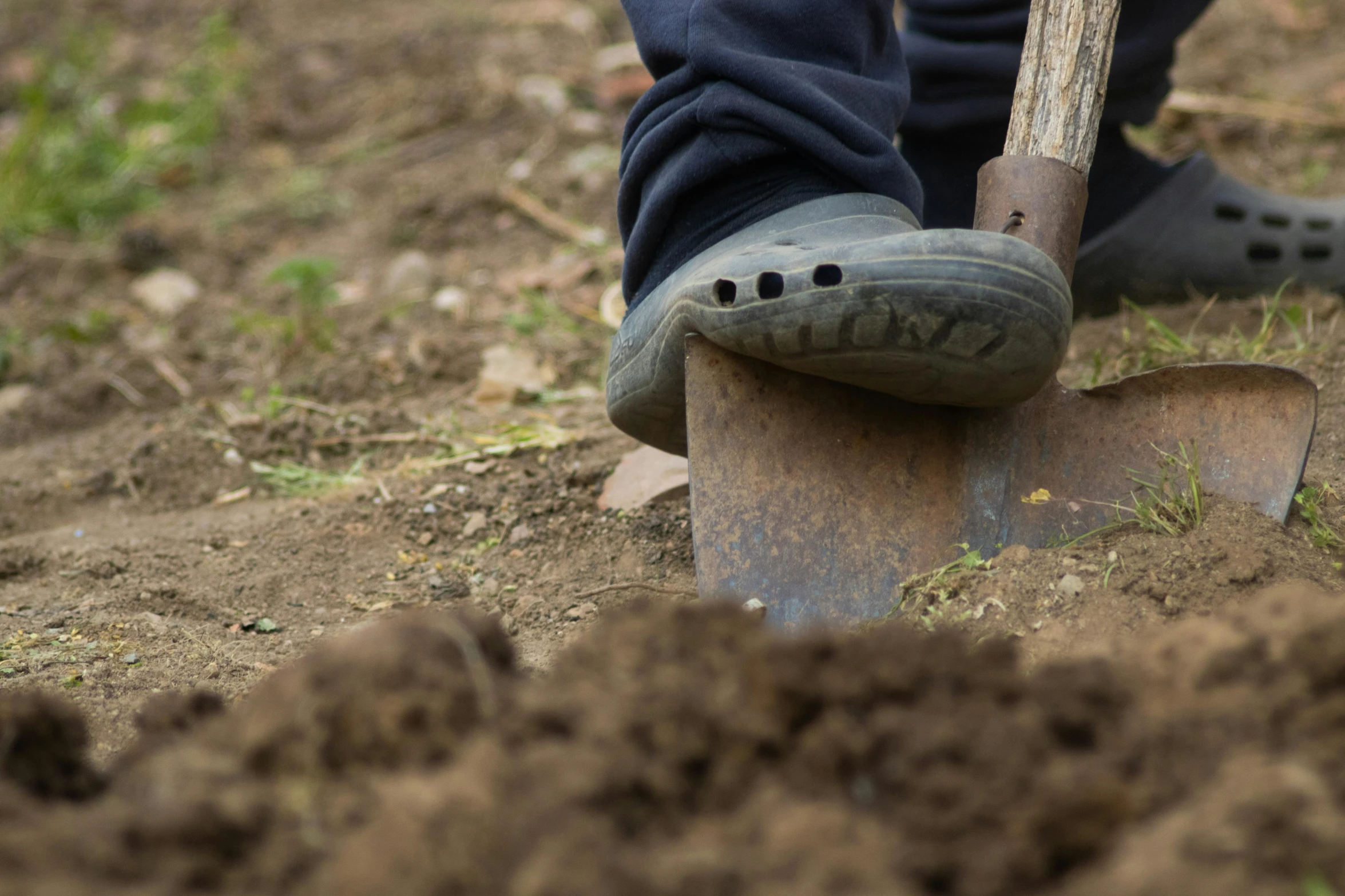 a person wearing cloggers digging in the ground