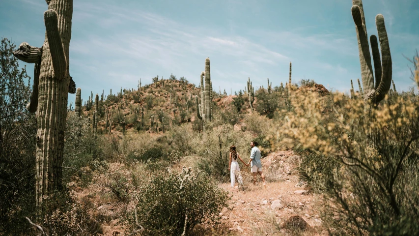 a man and woman walking along a desert landscape